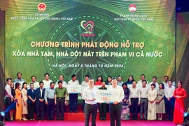 Ông Nguyễn Thanh Tùng (bên trái) - Bí thư Đảng ủy, Chủ tịch HĐQT Vietcombank trao tượng trưng kinh phí 100 tỷ đồng hỗ trợ xoá nhà tạm, nhà dột nát ủng hộ cho địa phương. (Ảnh: Vietnam+)