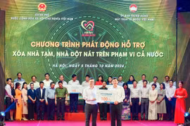 Ông Nguyễn Thanh Tùng (bên trái) - Bí thư Đảng ủy, Chủ tịch HĐQT Vietcombank trao tượng trưng kinh phí 100 tỷ đồng hỗ trợ xoá nhà tạm, nhà dột nát ủng hộ cho địa phương. (Ảnh: Vietnam+)