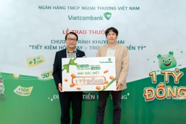 Anh Quang Nam (bên phải) nhận giải đặc biệt trị giá 1 tỷ đồng trong chương trình “Tiết kiệm hôm nay - Trúng ngay tiền tỷ” tại Vietcombank chi nhánh Tân Bình. (Ảnh: Vietnam+)