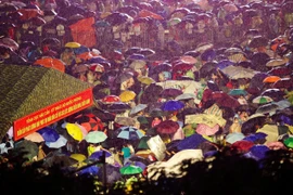 Tối 29/8, hàng trăm người mang áo mưa, chiếu, đồ ăn và nước uống đổ về các tuyến đường quanh quảng trường Ba Đình chờ xem sơ duyệt diễu binh diễu hành sáng mai (30/8). (Ảnh: PV/Vietnam+)