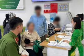 Đại diện Cơ quan công an và cán bộ Vietcombank đang giải thích và phân tích cho khách hàng. (Ảnh: Vietnam+)