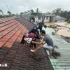 Lũ dâng cao, người dân phải phá mái nhà leo lên để tránh nguy hiểm ở Gia Lai. (Ảnh: TTXVN phát)