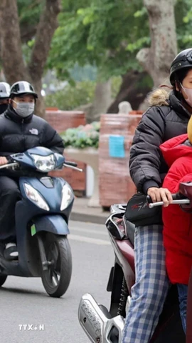 Người dân mặc áo khoác dáng dài và quàng khăn ấm khi di chuyển bằng xe máy qua khu vực hồ Hoàn Kiếm. (Ảnh: Vũ Quang/TTXVN)