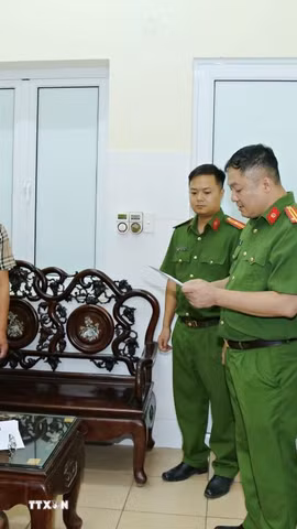 Cơ quan Cảnh sát điều tra, Công an tỉnh khám xét nơi làm việc của Hoàng Văn Huấn (áo kẻ). (Ảnh: TTXVN phát)