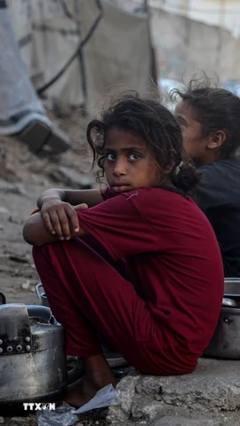 Trẻ em ngồi chờ nhận thức ăn cứu trợ ở thành phố Gaza. (Ảnh: THX/TTXVN)