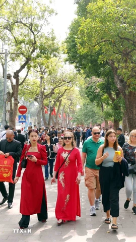 Du khách trong nước và quốc tế thảnh thơi du xuân bên hồ Hoàn Kiếm. (Ảnh: Phạm Kiên/TTXVN)