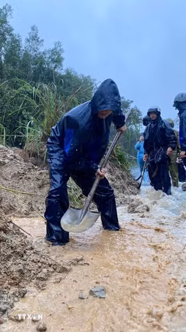 Các lực lượng đào, vét đất đá, mở rãnh thoát nước và thu dọn bùn đất tràn xuống mặt đường, tạo lối đi tạm để phương tiện qua lại. (Ảnh: TTXVN phát)