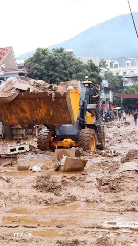 Máy xúc được huy động để hỗ trợ san gạt, thu gom bùn đất, cành cây, rác bị tràn về trong đợt lũ vừa qua tại xã Sông Mã. (Ảnh: Quang Quyết/TTXVN)