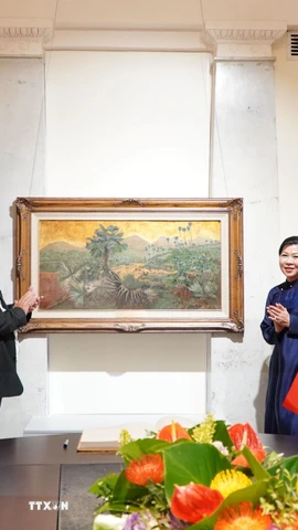 Phu nhân Ngô Phương Ly tặng bức tranh “Những đồi cọ” của cố họa sỹ Phan Kế An. (Ảnh: Tâm Hằng/TTXVN)