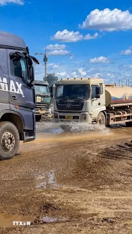 Đơn vị thi công tăng cường bố trí liên tục các xe chuyên dụng thay nhau tưới nước dọc các tuyến đường công vụ nhằm hạn chế tối đa tình trạng bụi bay vào khu dân cư. (Ảnh: TTXVN phát)