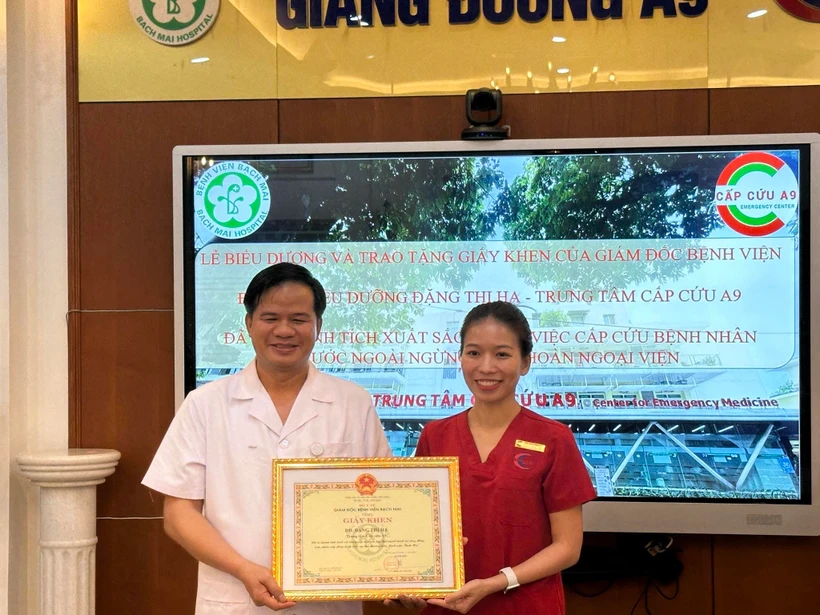 Phó giáo sư Đào Xuân Cơ trao giấy khen cho nữ điều dưỡng Đặng Thị Hạ. (Ảnh: PV/Vietnam+)