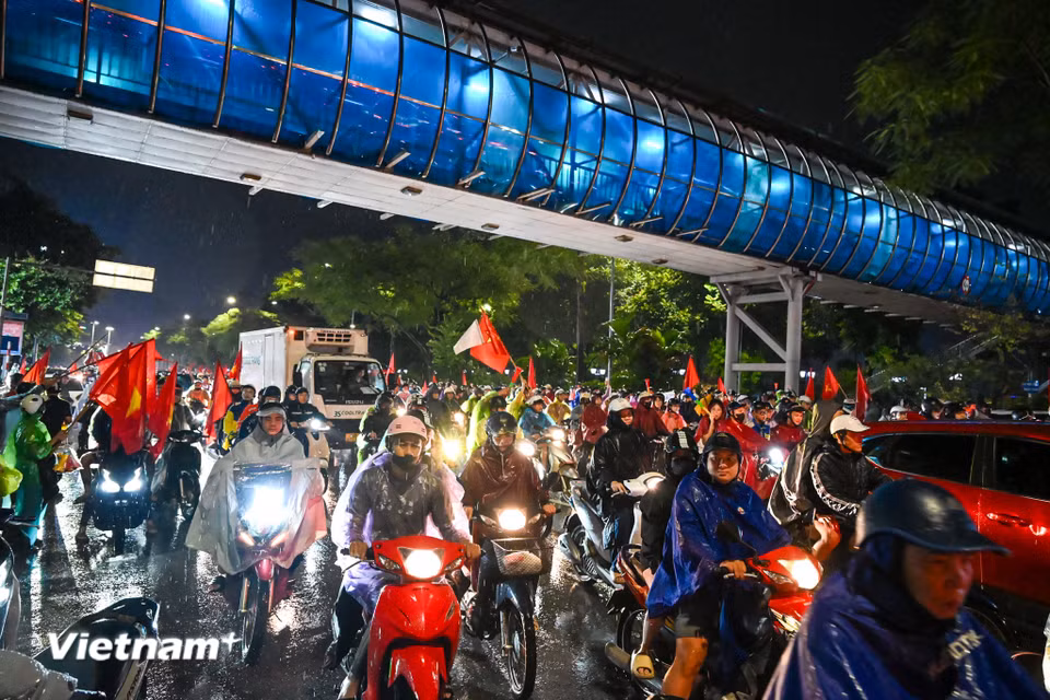 Dù trời mưa nặng hạt, những tuyến phố trung tâm Thủ đô vẫn rực sắc đỏ của cờ Tổ quốc, tiếng hò reo “Việt Nam vô địch” vang lên không ngớt. (Ảnh: Minh Sơn/Vietnam+)