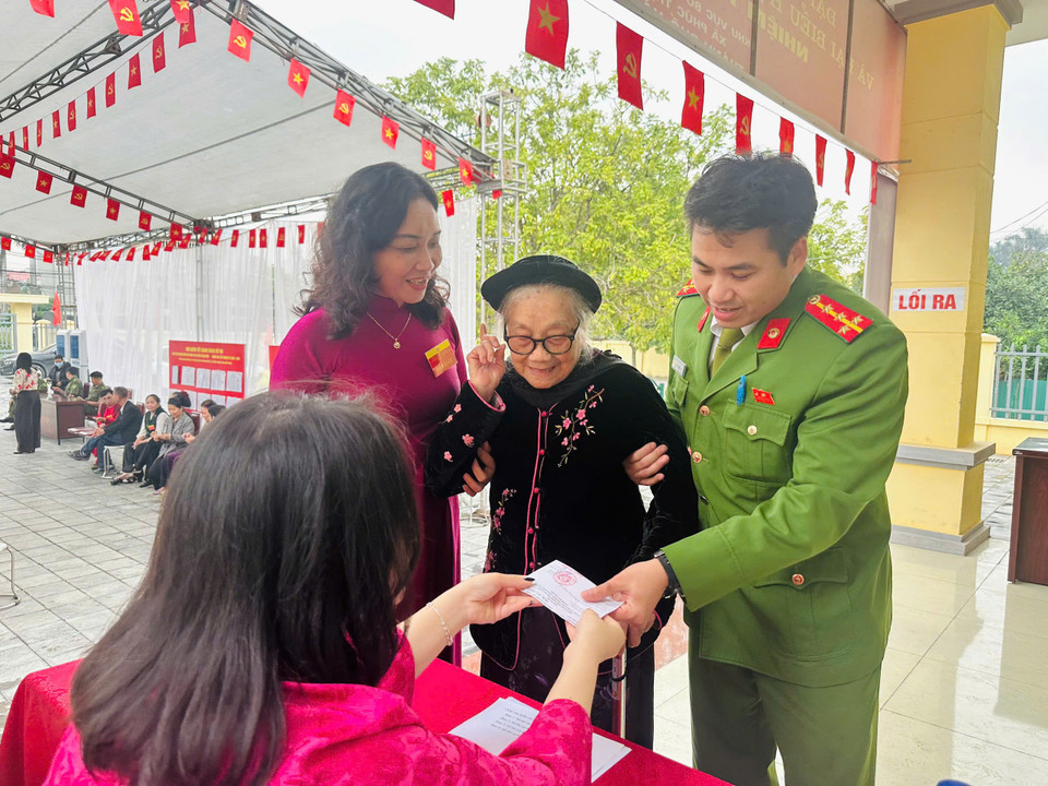 Công an xã Phúc Thịnh hướng dẫn các cư tri cao tuổi thực hiện việc bỏ phiếu. (Ảnh: CAHN)
