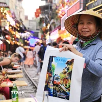 Một người hàng rong bán tranh in "phố càphê đường tàu." (Ảnh: Thành Phương/TTXVN)