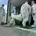 Các nhân viên chuyển thi thể binh sỹ Ukraine từ xe vận chuyển đông lạnh để hồi hương gần Novaya Guta, Belarus vào ngày 19/8. (Nguồn: AP)