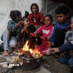 Trẻ em Palestine sưởi ấm tại khu lều trại tạm ở thành phố Gaza. (Ảnh: THX/TTXVN)