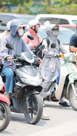 Khẩu trang, áo chống nắng là những thứ không thể thiếu của người dân khi tham gia giao thông. (Ảnh: Lê Đông/TTXVN)