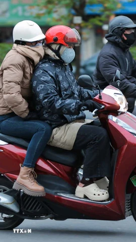 Người dân mặc áo ấm, khẩu trang, khăn quàng cổ, găng tay khi phải di chuyển ngoài trời. (Ảnh: Hoàng Hiếu/TTXVN)