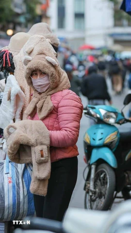 Người lao động, bán hàng trên phố che chắn kỹ chống rét. (Ảnh: Hoàng Hiếu/TTXVN)