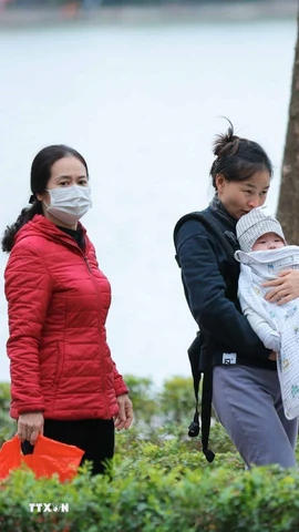 Trẻ nhỏ được che chắn kỹ chống rét khi phải di chuyển ngoài trời. (Ảnh: Hoàng Hiếu/TTXVN)