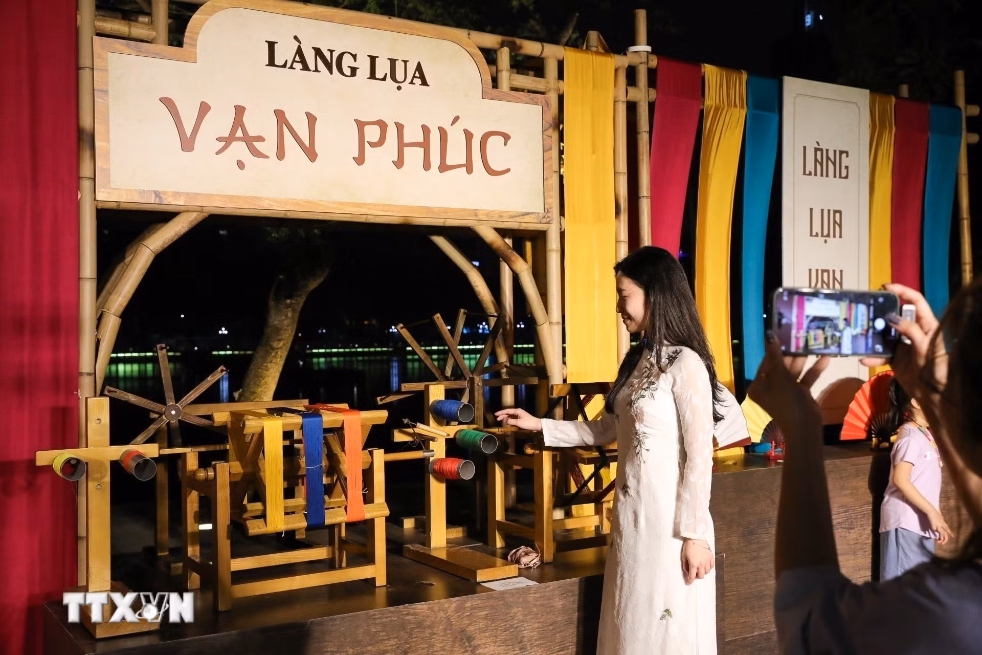 Người dân chụp ảnh lưu lại khoảnh khắc tại gian trưng bày của Làng lụa Vạn Phúc. (Ảnh: Khánh Hòa/TTXVN)