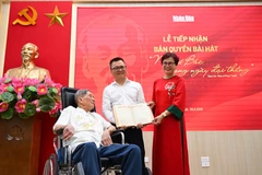 Tổng Biên tập Lê Quốc Minh nhận bản thảo bài hát "Như có Bác trong ngày đại thắng" có chữ ký đề tặng của nhạc sỹ Phạm Tuyên. (Ảnh: CTV/Vietnam+) 