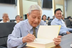 Nhà báo Hà Đăng ký tặng tại Lễ ra mắt sách. (Ảnh: PV/Vietnam+)