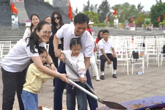 Gia đình anh Bùi Văn Quyết và chị Vũ Thanh Tâm tham gia trồng cây Hạnh phúc. (Ảnh: Dũng Vũ/Vietnam+)