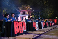 Các "thầy đồ" cho chữ tại không gian Văn Miếu-Quốc Tử Giám. (Ảnh: Phạm Sỹ/Vietnam+)