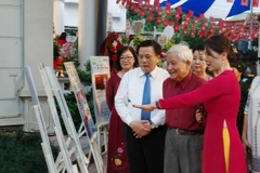 Ông Nguyễn Xuân Thắng, Ủy viên Bộ Chính trị, Giám đốc Học viện Chính trị Quốc gia Hồ Chí Minh; nhà báo lão thành Hà Đăng cùng các đại biểu tham quan triển lãm. (Ảnh: Nam Sương/TTXVN)