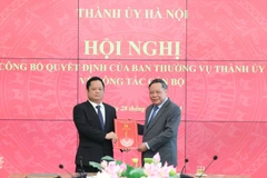 Phó Bí thư Thường trực Thành ủy Hà Nội Nguyễn Văn Phong trao quyết định của Ban Thường vụ Thành ủy Hà Nội và tặng hoa chúc mừng ông Vũ Minh Tuấn. (Ảnh: Quang Thái)