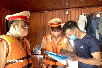 Lực lượng Cảnh sát giao thông đường thủy hướng dẫn các chủ phương tiện ký cam kết chấp hành nghiêm Luật Giao thông đường thủy. (Ảnh: Nguyễn Thảo/Vietnam+)