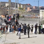 Người di cư trèo qua hàng rào biên giới để vào vùng lãnh thổ Ceuta của Tây Ban Nha từ thành phố Fnideq, Maroc. (Ảnh: THX/TTXVN phát)