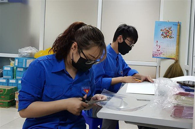 Đoàn thanh niên phường Cống Vị tự làm kính chắn giọt bắn trang bị cho các lực lượng tham gia phòng, chống dịch COVID-19 trên địa bàn. (Ảnh: TTXVN) Hà Nội triển khai chiến dịch 10.000 việc làm, chống thất nghiệp ảnh 1