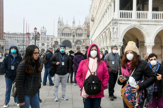 Khách du lịch đeo khẩu trang phòng dịch viêm đường hô hấp cấp COVID-19 tại Venice, Italy ngày 25/2/2020. (Ảnh: AFP/TTXVN) Italy không đóng cửa biên giới, các nước phối hợp ứng phó với COVID-19 ảnh 1