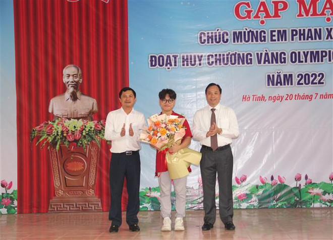 Lãnh đạo tỉnh Hà Tĩnh tặng hoa chúc mừng em Phan Xuân Hành. (Ảnh: Hoàng Ngà/TTXVN) Cậu học trò miền núi và hành trình chạm tới HCV Olympic Hóa học ảnh 2