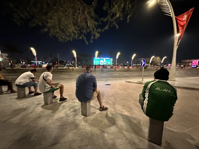 Những người lao động nhập cư đang xem World Cup từ vỉa hè. (Nguồn: Thể thao và Văn hóa) World Cup 2022: Khi trái bóng tròn lăn trên vỉa hè thủ đô Doha ảnh 1