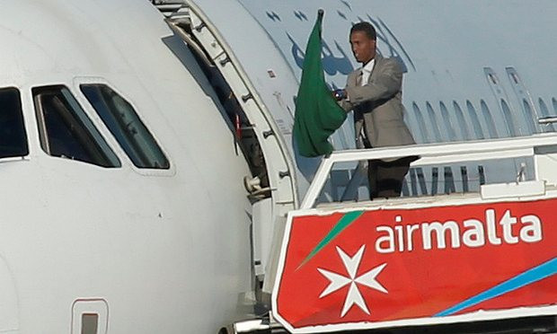 Một trong hai tên không tặc cầm lá cờ ở bên ngoài máy bay. (Nguồn: Reuters) Vụ cướp máy bay Libya: Hai kẻ không tặc đầu hàng, bị bắt giữ ảnh 1
