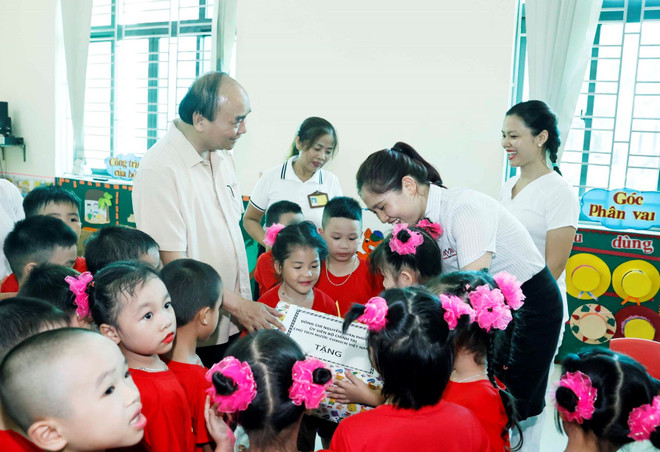 Chủ tịch nước Nguyễn Xuân Phúc tặng quà cho con em công nhân Công ty trách nhiệm hữu hạn thương mại Sao Mai, huyện Vĩnh Bảo, thành phố Hải Phòng. (Ảnh: Thống Nhất/TTXVN) Chủ tịch nước thăm mô hình kinh doanh dệt may hiệu quả ở Hải Phòng ảnh 2