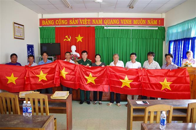 Đồn Biên phòng Tân Thành và UBND xã Tân Thành tặng cờ Tổ quốc cho 8 chủ phương tiện đã tham gia cứu hộ, cứu nạn. (Ảnh: Hữu Chí/TTXVN) Khen thưởng 8 chủ phương tiện và ngư dân quên mình cứu nạn trên biển ảnh 1