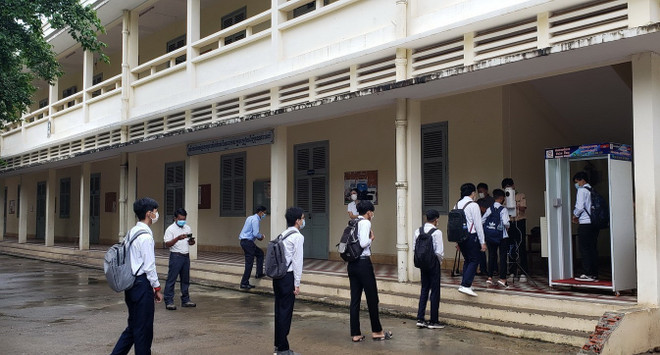 Học sinh trường Trung học Preah Yukunthor , Phnom Penh xếp hàng giãn cách và khử khuẩn trước khi lên lớp học. (Ảnh: Vũ Hùng/PV TTXVN) Hàng chục nghìn học sinh Campuchia bắt đầu tựu trường ảnh 1