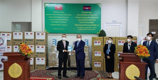 Đại sứ Vũ Quang Minh đại diện Việt Nam (trái) bàn giao máy thở, vật tư y tế hỗ trợ Campuchia chống dịch COVID-19 cho Bộ trưởng Bộ Y tế Campuchia. (Ảnh: Nguyễn Vũ Hùng/TTXVN) Bộ Y tế Campuchia tiếp nhận máy thở và vật tư y tế do Việt Nam hỗ trợ ảnh 1
