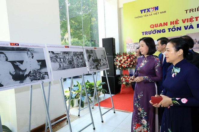 Tổng giám đốc TTXVN Vũ Việt Trang cùng các đại biểu tham quan triển lãm ảnh 'Quan hệ Việt-Lào: Trường tồn và phát triển.' (Nguồn: TTXVN) Tạo động lực mạnh mẽ tăng cường quan hệ giữa Việt Nam và Lào ảnh 2