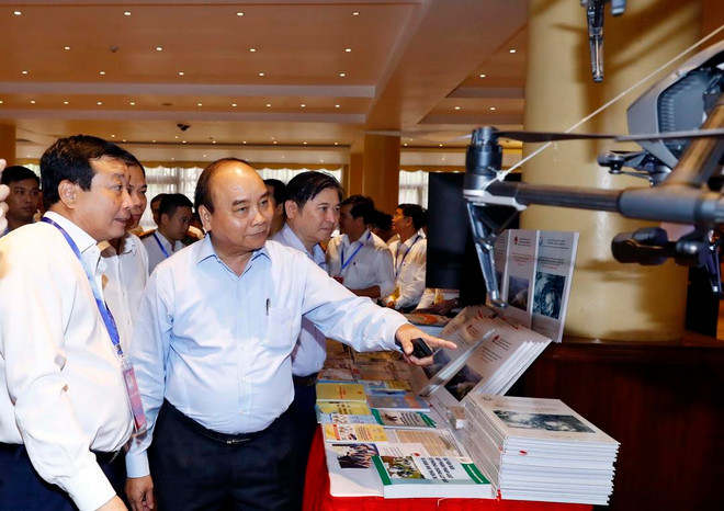 Thủ tướng Nguyễn Xuân Phúc và các đại biểu tham quan triển lãm công nghệ phòng chống thiên tai được trưng bày tại hội nghị. (Ảnh: Thống Nhất/TTXVN) Thủ tướng: Nâng cao chất lượng công tác dự báo, cảnh báo thiên tai ảnh 2