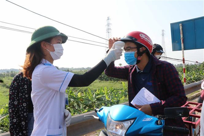 Kiểm tra thân nhiệt tại chốt kiểm soát dịch COVID-19 tại Quốc lộ 38, huyện Thuận Thành, tỉnh Bắc Ninh. (Ảnh: Thanh Thương/TTXVN) Những 'lá chắn sống' trên mặt trận phòng, chống dịch COVID-19 ảnh 2