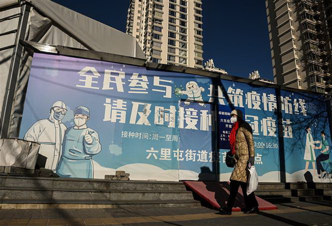 Người dân đeo khẩu trang phòng lây nhiễm COVID-19 ở Bắc Kinh, Trung Quốc. (Ảnh: AFP/TTXVN) Nhìn lại thế giới năm 2022: Ứng phó với nguy cơ 'dịch chồng dịch' ảnh 1