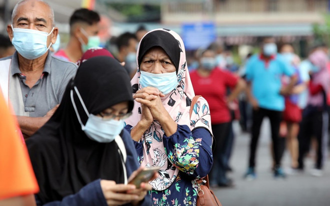 Người dân xếp hàng chờ làm xét nghiệm tại TP Klang, Malaysia. (Ảnh: Reuters) Quốc hội Malaysia được phép nhóm họp trong tình trạng khẩn cấp ảnh 1
