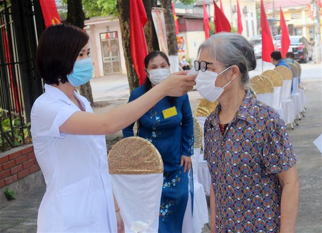 Các cử tri trước khi vào bầu cử được thực hiện khai báo y tế và đo thân nhiệt. (Ảnh: TTXVN) Các địa phương đảm bảo an toàn bầu cử và phòng, chống dịch ảnh 1