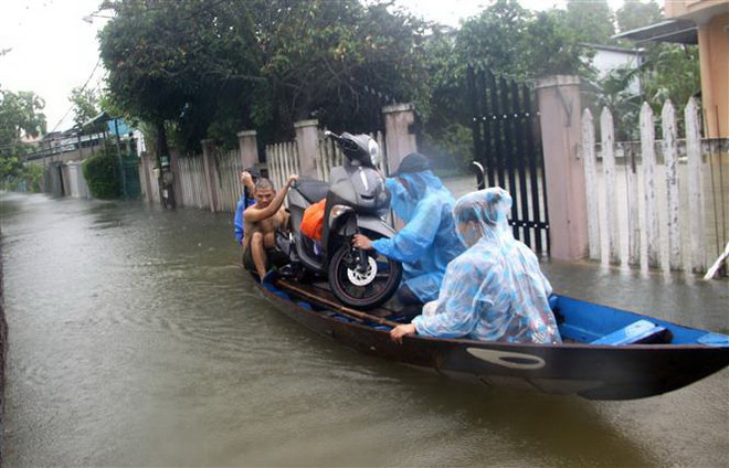 Người dân dùng thuyền di chuyển tài sản đến cất ở nơi khô ráo. (Ảnh: Trịnh Bang Nhiệm/TTXVN) Tình trạng ngập lụt ở miền Trung còn kéo dài trong những ngày tới ảnh 1