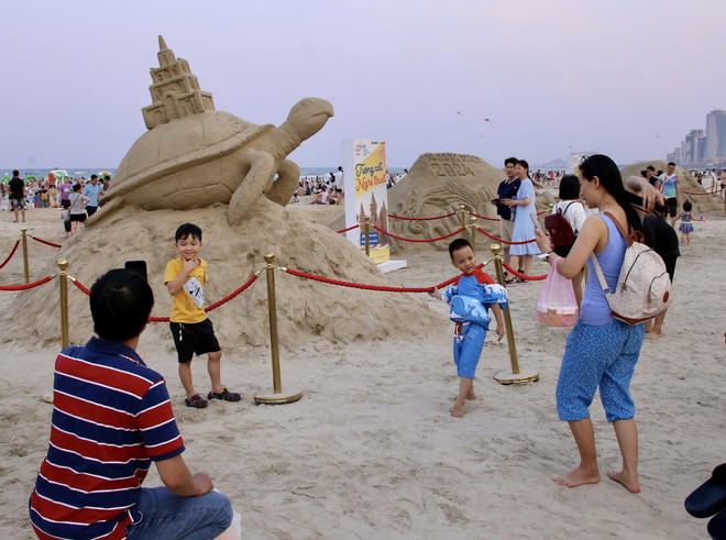 Du khách vui chơi chụp ảnh tại khu vực tượng cát trên bãi biển Đà Nẵng. (Ảnh: Trần Lê Lâm/TTXVN) ttxvn_du lich da nang 2.jpg